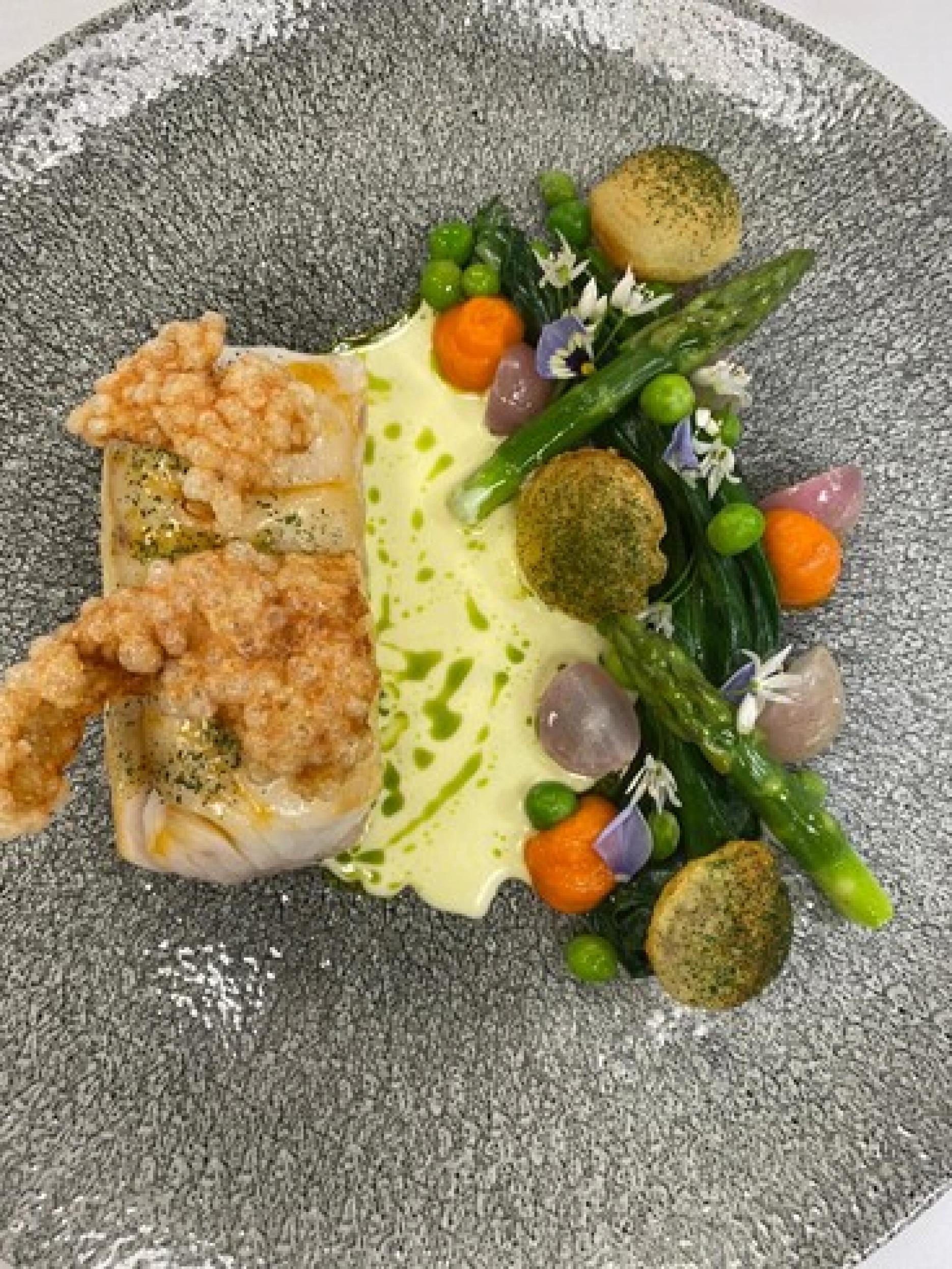 Charlie’s dish is a cod poached in lobster butter, lobster tapioca crisp, seasonal vegetables, pomme souffles, carrot puree and split butter sauce.